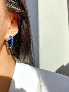 Close-up of model wearing blue enamel C-shape hoop earrings with sparkling cubic zirconia
