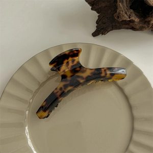 Close-up of tortoise shell hair claw clip on ceramic dish with handmade engraving