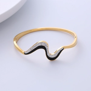 Detailed view of wave-shaped gold bangle featuring black and white rhinestone pave setting