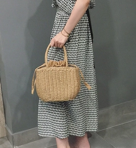 Detail of hand-woven straw tote bag with brown drawstring lining and top handles