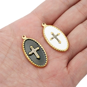 Detailed close-up of 18k gold-plated oval cross pendants with black and white enamel finish