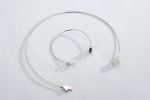 Detailed top view of silver titanium steel cross and heart open bangle and necklace set