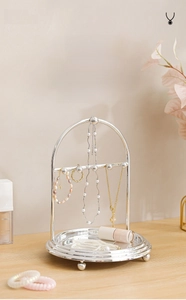 Detailed close-up of a silver metal jewelry display stand with hooks and tray for necklaces