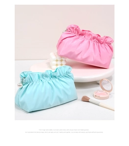 Dettaglio di trousse per trucchi arricciate rosa e blu con eleganti ciondoli a perla