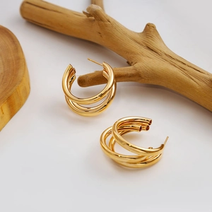 Close-up of golden triple-layered C-shaped geometric hoop earrings with polished finish