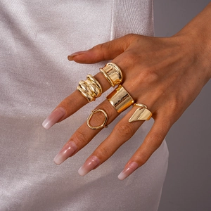 Detailed view of five-piece gold geometric rings on hand with various textures