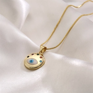 Macro shot of gold circular evil eye pendant with colorful cubic zirconia on silk