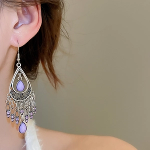 Detail of purple teardrop tassel earrings in vintage silver with bohemian hollow patterns