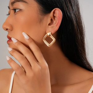 Gros plan d'un mannequin portant d'élégantes boucles d'oreilles carrées dorées