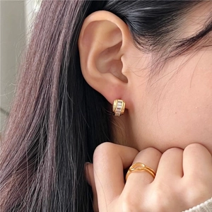 Close-up of elegant gold square zircon earrings and matching twisted ring on a model