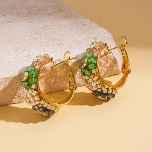 Détail de créoles dorées avec perles de verre multicolores et strass sur pierre
