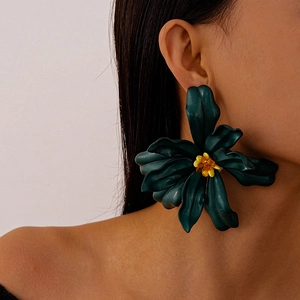 Detail of oversized dark green acrylic flower earrings with amber bead center on model