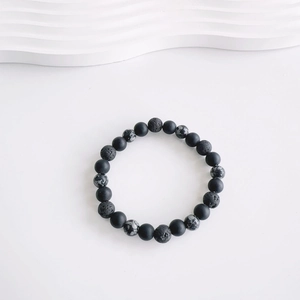 Detailed view of matte black beads and porous volcanic stone on an adjustable cord bracelet