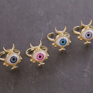 Exaggerated 18K gold evil eye rings with colorful enamel details in a diagonal display