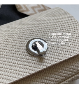 Close-up of woven fabric crossbody bag with silver twist lock and wavy shoulder strap