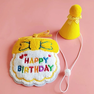 Detail of yellow plush pet birthday bib and hat set with rainbow embroidery text