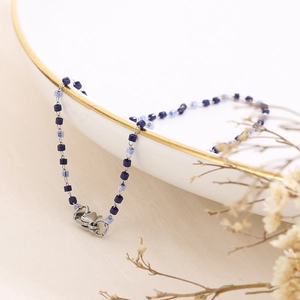 Close-up of blue resin beaded chain with silver lobster clasp on a white plate