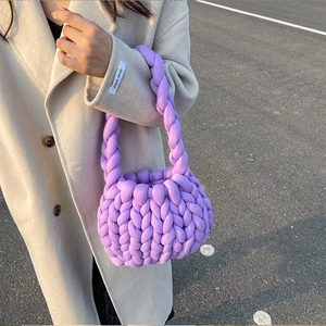 Chunky knit purple handmade handbag styled with a beige coat in an outdoor setting