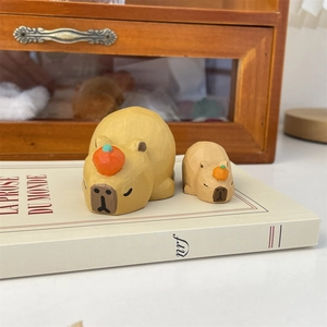 Detailed view of hand-carved wood capybara desktop figures with orange decorations