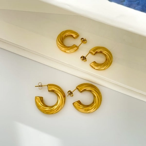 Polished gold twisted C-shape hoop earrings with a glossy spiral texture on white background