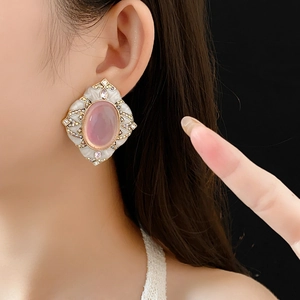 Detail of vintage diamond earrings with pink oval gemstone and gold frame on model