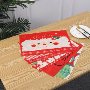Detailed view of stackable festive Christmas placemats with Santa Claus pattern on table.