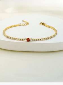 Detail of titanium steel gold bracelet with square red gemstone and cubic zirconia