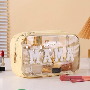 Close-up of yellow transparent PVC toiletry bag with MAMA embroidered letters and gold zipper