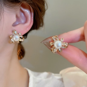 Detailed view of elegant gold bow stud earrings with pearls and shimmering zircon stones