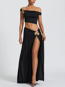 Detail of black two-piece dress featuring gold metallic flower ornaments on waist and shoulder