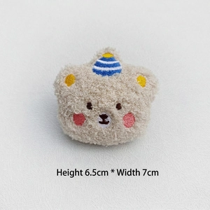 Detailed view of plush bear badge with birthday hat showing 6.5cm height and embroidery