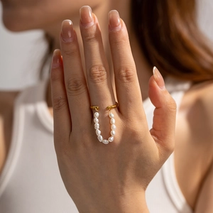 Detailed view of a gold stainless steel ring featuring a hanging white pearl chain