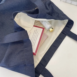 Dettaglio della borsa tote in denim blu scuro con fodera crema e tasca interna a zip