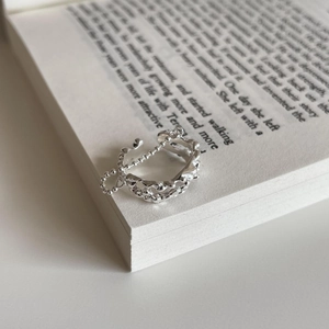 Detailed view of silver 925 irregular wavy ring with chain on an open book page