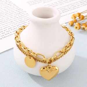 Gold heart pendant double-layer chain bracelet displayed on a white ceramic vase with dried flowers