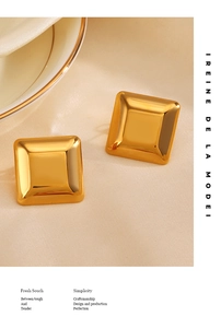 Macro detail of polished gold square stud earrings on a minimalist textured background