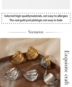 Macro view of geometric fan earrings with PVD gold plating on a ceramic tray