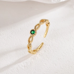 Detail of 18K gold-plated twisted ring featuring a round green zircon on stone background