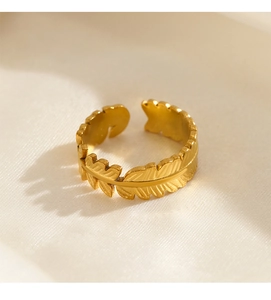 Detail of 18K gold plated leaf ring with adjustable band on textured beige fabric