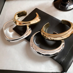 Détails de bracelets manchettes en métal doré et argenté sur pochette en cuir noir