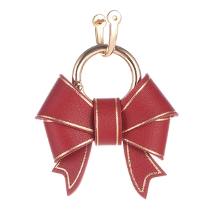 Fashionable red faux leather bow keychain with gold edges and metal ring on white background