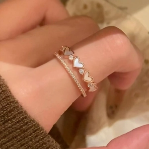 Detail of rose gold double-layered heart rings with mother of pearl and zircons