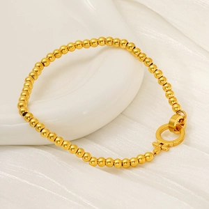 Détail du bracelet à perles plaqué or 18 carats avec fermoir circulaire sur fond blanc