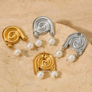 Boucles d'oreilles spirales dorées et argentées avec perles sur fond de pierre
