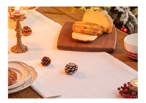 Close-up of a white plush Christmas table runner on dark wood with warm festive lighting