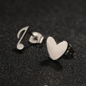 Macro shot of silver musical note and heart stud earrings in brushed stainless steel