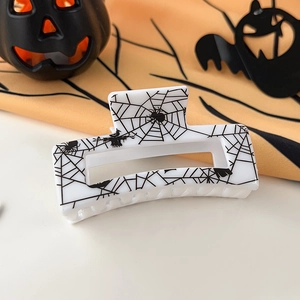 Close-up of white Halloween hair claw clip with spider web and scarecrow prints