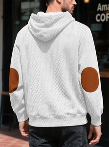 Détail d'un sweat à capuche blanc texturé avec écussons marrons circulaires aux coudes