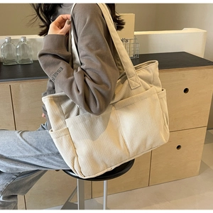 Détail d'un cabas en velours côtelé crème montrant la texture et les poches avant