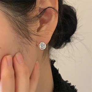 Close-up of a minimalist silver organic-shaped stud earring worn on model's ear